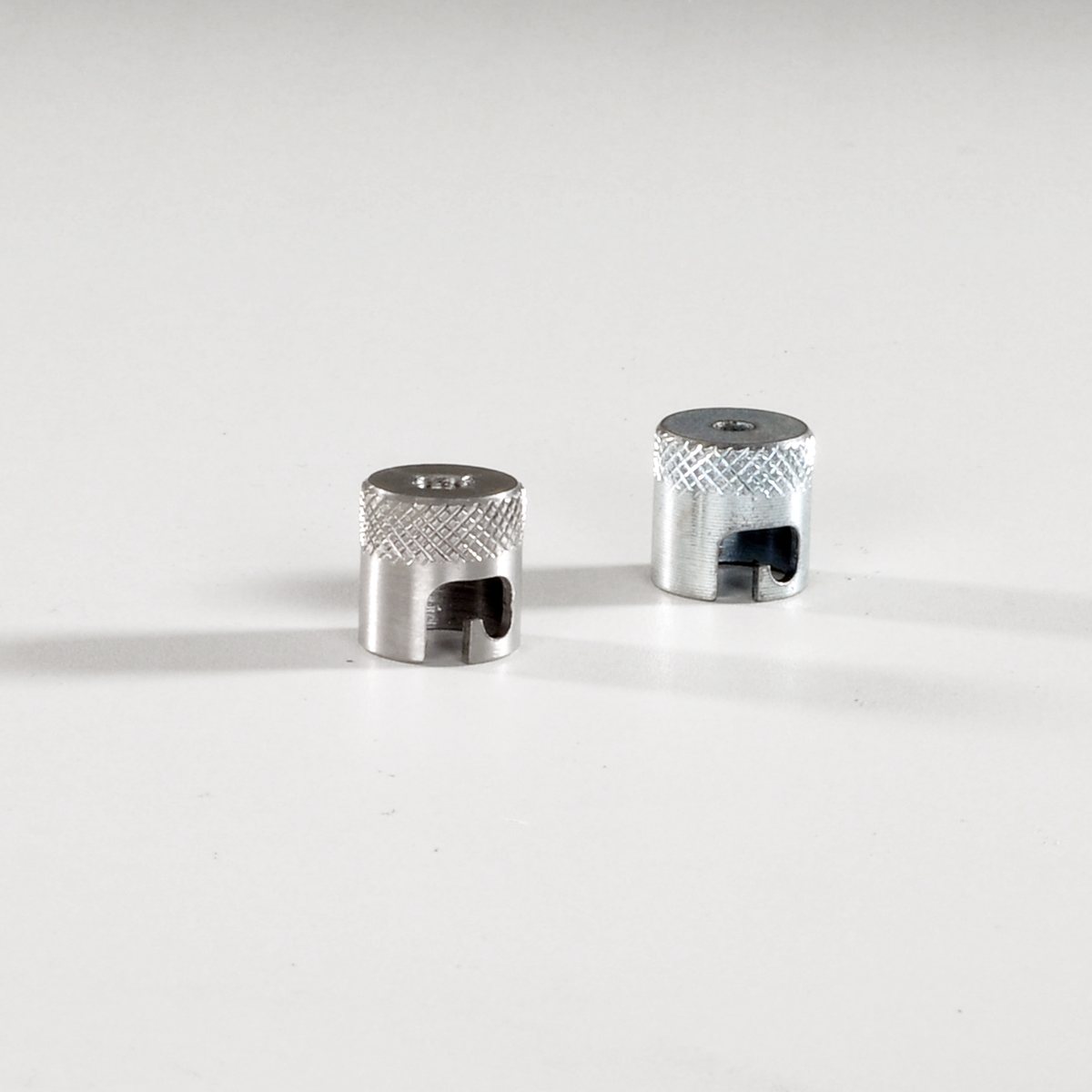 Two knurled bayonet caps showing the J-slot