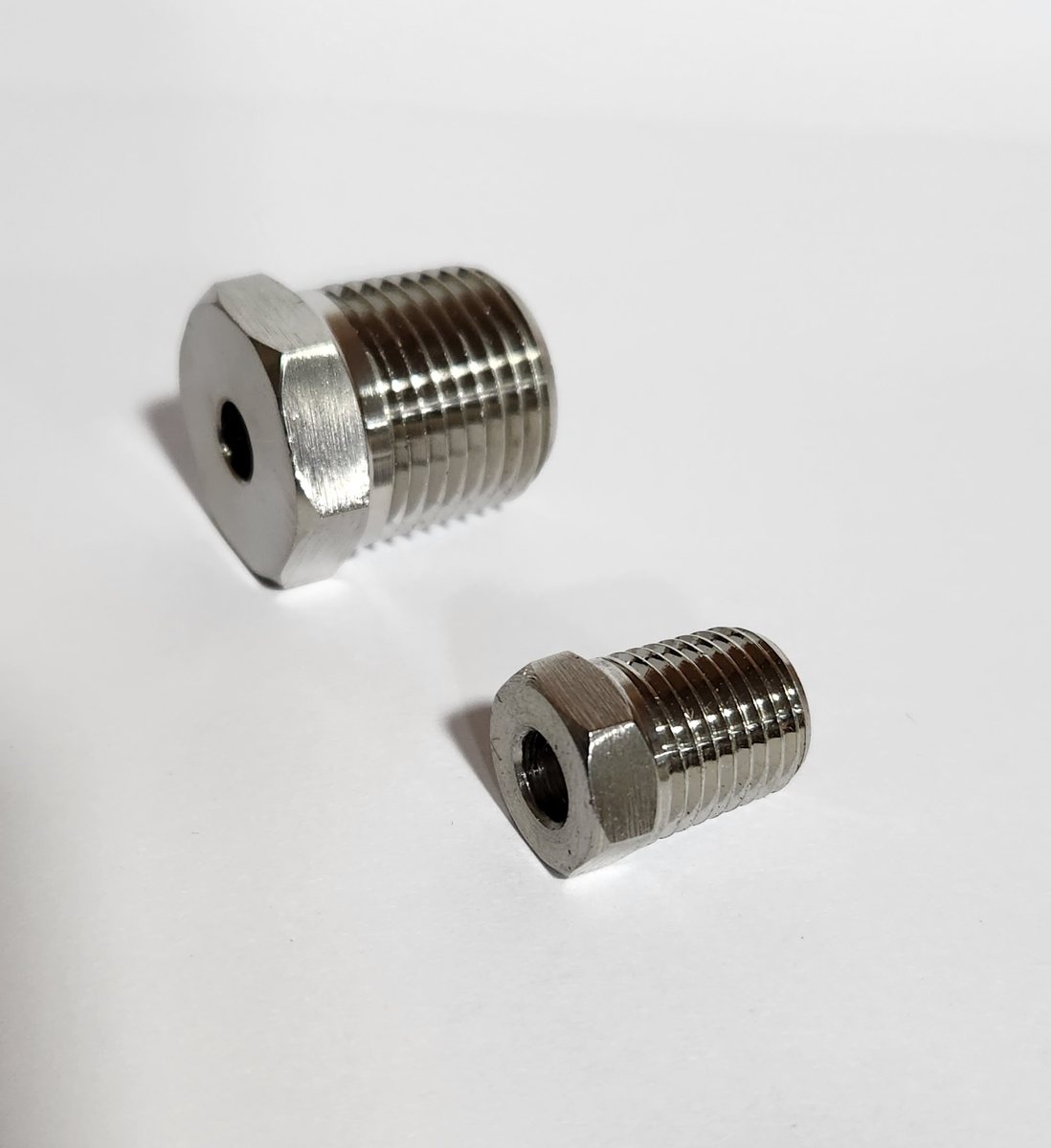 Two stainless steel potting plugs with hex heads
